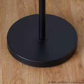 Close-up of a matte black circular base and central pole on a light brown wood floor, with a small LumSource copyright watermark in the lower right corner.