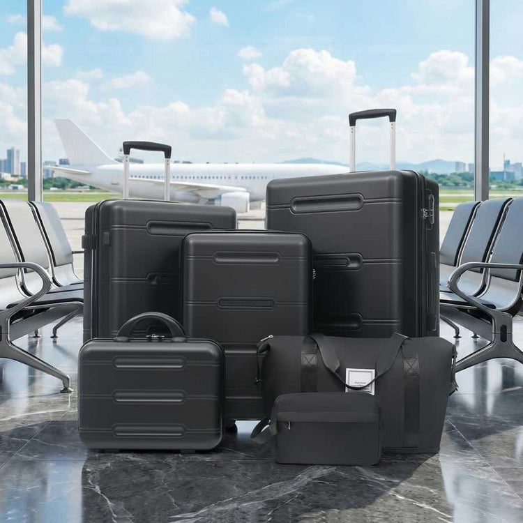 Set of black suitcases in an airport terminal with a plane visible through the window.