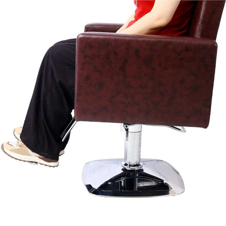 Side view of person sitting on salon chair, showcasing armrest height and seat depth for optimal client positioning.