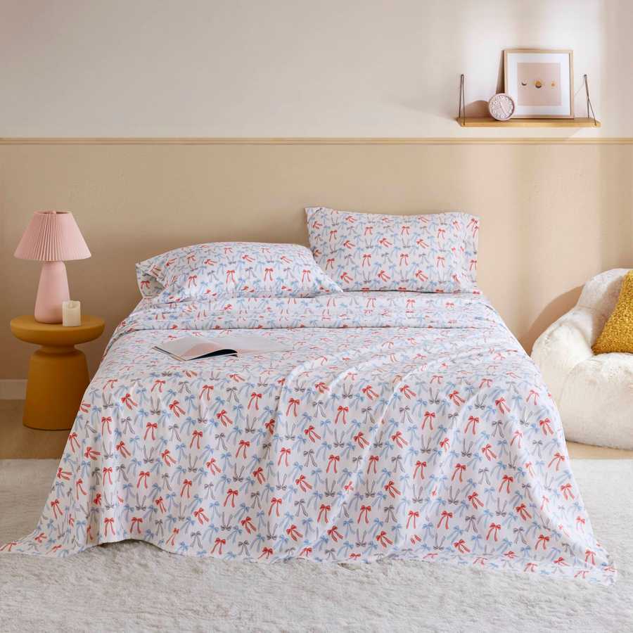 Happy Bows Twin XL Cotton Flannel Sheet Set on bed with colorful bow print, ideal for cozy dorm or guest room bedding.