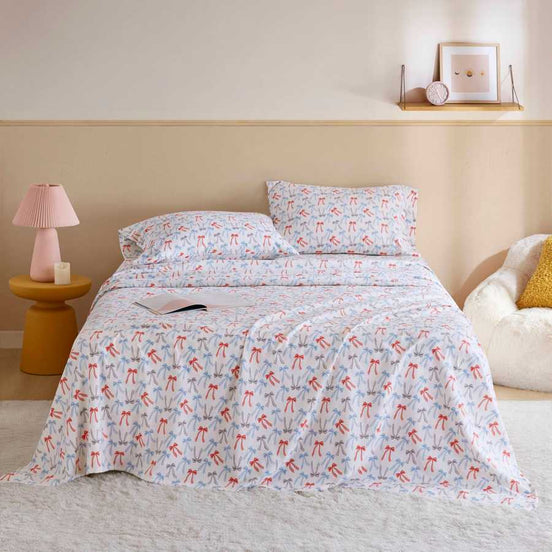 Happy Bows Twin XL Cotton Flannel Sheet Set on bed with colorful bow print, ideal for cozy dorm or guest room bedding.