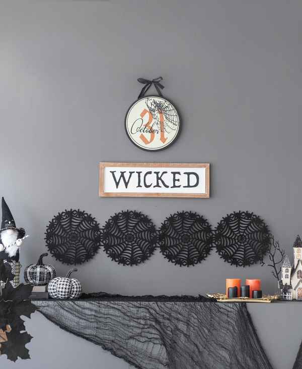 Halloween circle sign with spiderweb and October 31, hanging on a wall above Halloween themed decorations and &