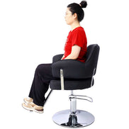 Hair professional seated on Salon Styling Chair with black PU leather and chrome base, demonstrating comfort and functionality.