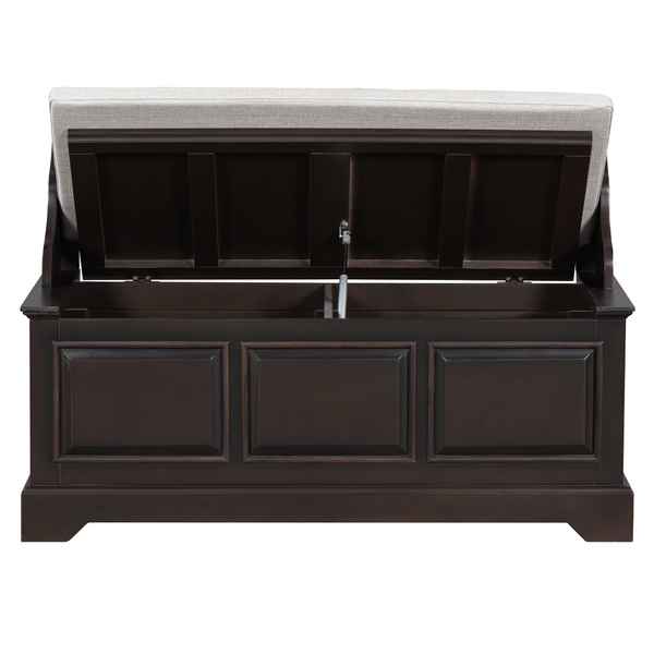 A dark brown wooden storage bench with a light beige upholstered seat cushion, shown with the lid open to reveal storage space inside.
