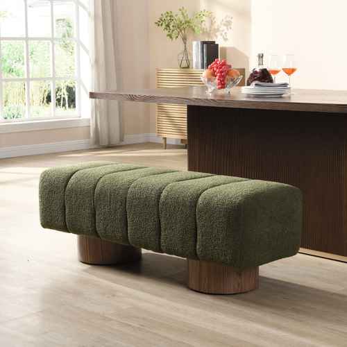 An olive green boucle tufted bench with round wooden legs, positioned in a modern living room setting in front of a dark wood dining table.