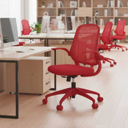 Red office chair in a modern office setting with desks and computers.
