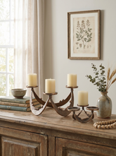 Two rustic metal candle holders with cream pillar candles displayed on a wooden sideboard in a styled room setting.
