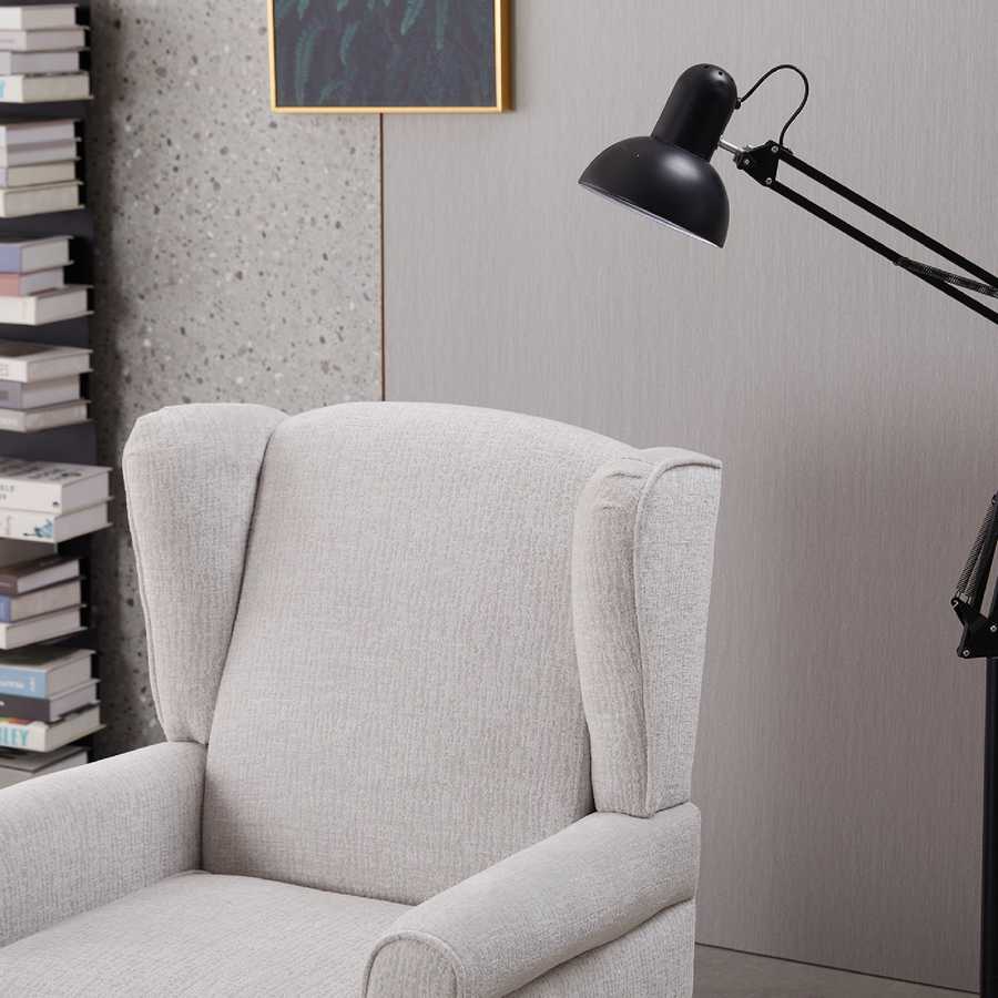 Gray armchair with a black lamp against a gray wall