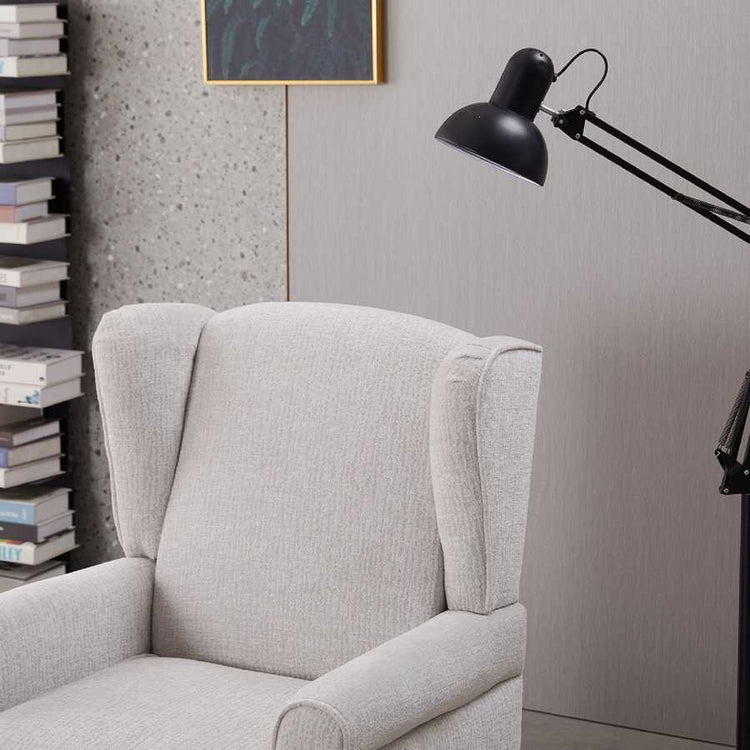 Gray armchair with a black lamp against a gray wall