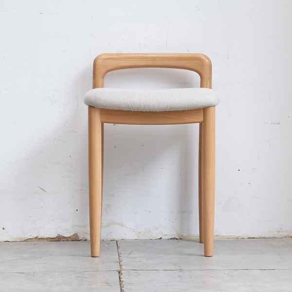 Wooden chair with a white cushion against a plain white wall.