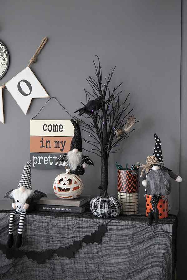 Halloween interior decoration with black and white gnome figures, black web, bats, and spooky accents creating a festive atmosphere.
