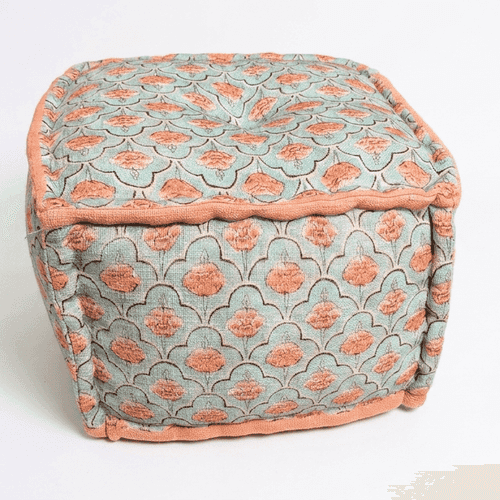 A square tufted pouf ottoman with a muted sage green fabric covered in a coral-pink floral pattern, finished with a solid coral-pink piped edge.