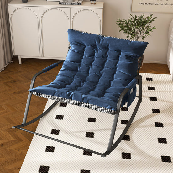 Blue cushioned chair on a patterned rug in a room with a white cabinet and plant.