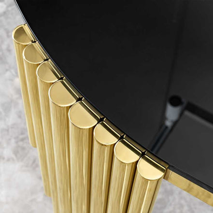 Detail of gold stainless steel leg design on black glass oval dining table, showcasing modern craftsmanship.