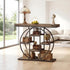 A rustic dark wood and metal console table styled in a bright, modern living room. The table features a thick distressed dark wood top, a large circular metal frame, and multiple open shelves holding wicker baskets, a vintage radio, a globe, and decorative items.
