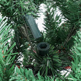 Close-up of a green artificial Christmas tree branch with plastic needle-like leaves and a dark green hexagonal connector at the base.
