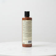 One N Only Argan Oil Color Oasis Smoothing Conditioner bottle placed on a marble surface, back label with product details visible.