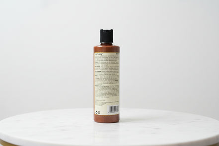 One N Only Argan Oil Color Oasis Smoothing Conditioner bottle placed on a marble surface, back label with product details visible.