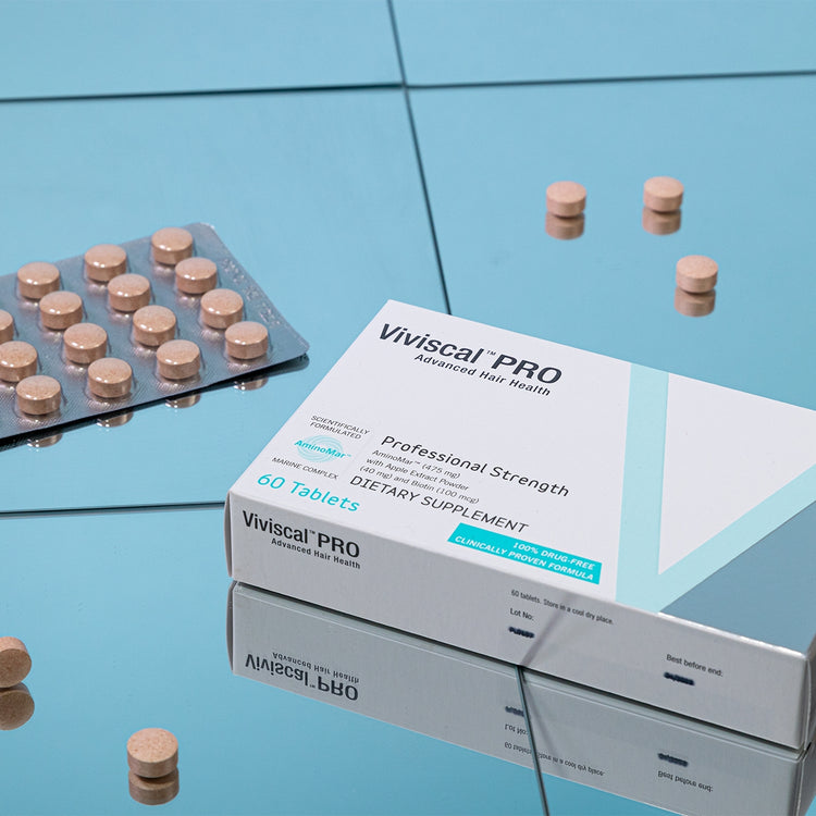 Viviscal Pro supplement box with tablets on a reflective blue surface