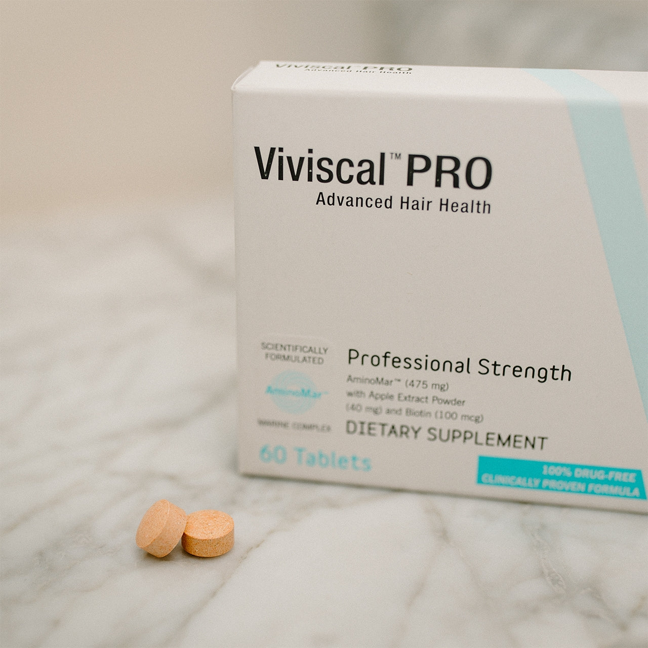 Viviscal Pro dietary supplement box with tablets on a marble surface