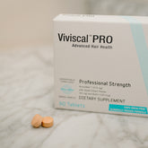 Viviscal Pro dietary supplement box with tablets on a marble surface