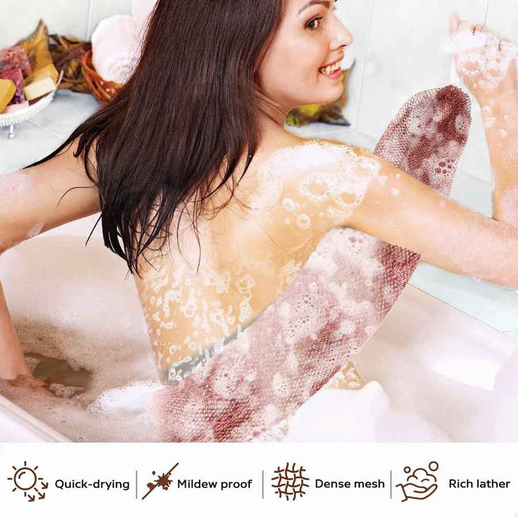 Woman in a bathtub with bubbles, surrounded by bath products.
