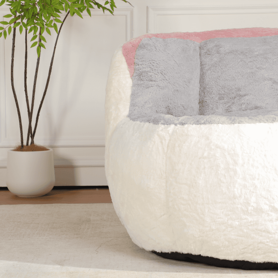 White and gray textured bean bag chair with pink accent in a room with a plant.
