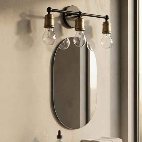 A three-light wall sconce with clear bulb-shaped glass shades and antique brass fittings mounted above an oval wall mirror on a textured beige wall.