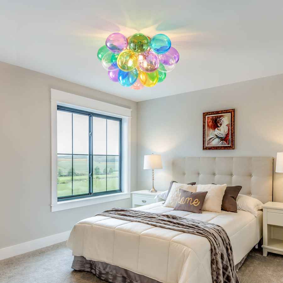 Modern bedroom with colorful ceiling light fixture, bed, and window view.