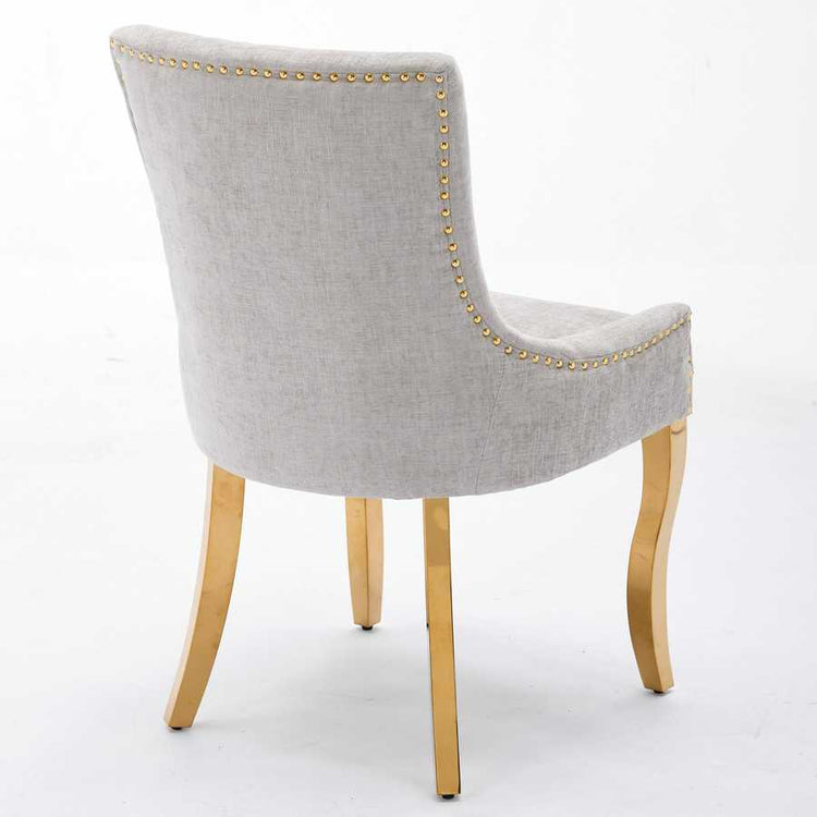 Gray upholstered chair with gold nailhead trim and wooden legs on a white background
