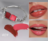 A silver chain bracelet holding a lipstick tube with two red shades, shown alongside two close-up lip swatches wearing the lipstick and two lipstick smears on a light gray background. Text reads &