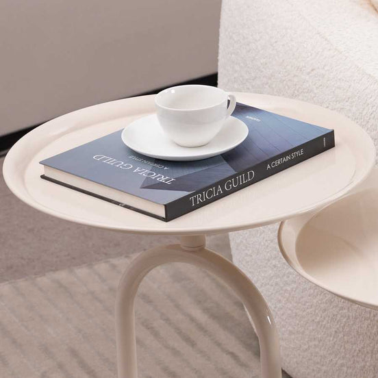 Small metal end table styled with a book and teacup, showcasing its use as a modern accent table in cozy living areas.