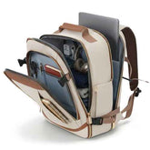 A beige and brown backpack shown open, filled with a laptop, headphones, and other accessories, photographed on a clean white background.