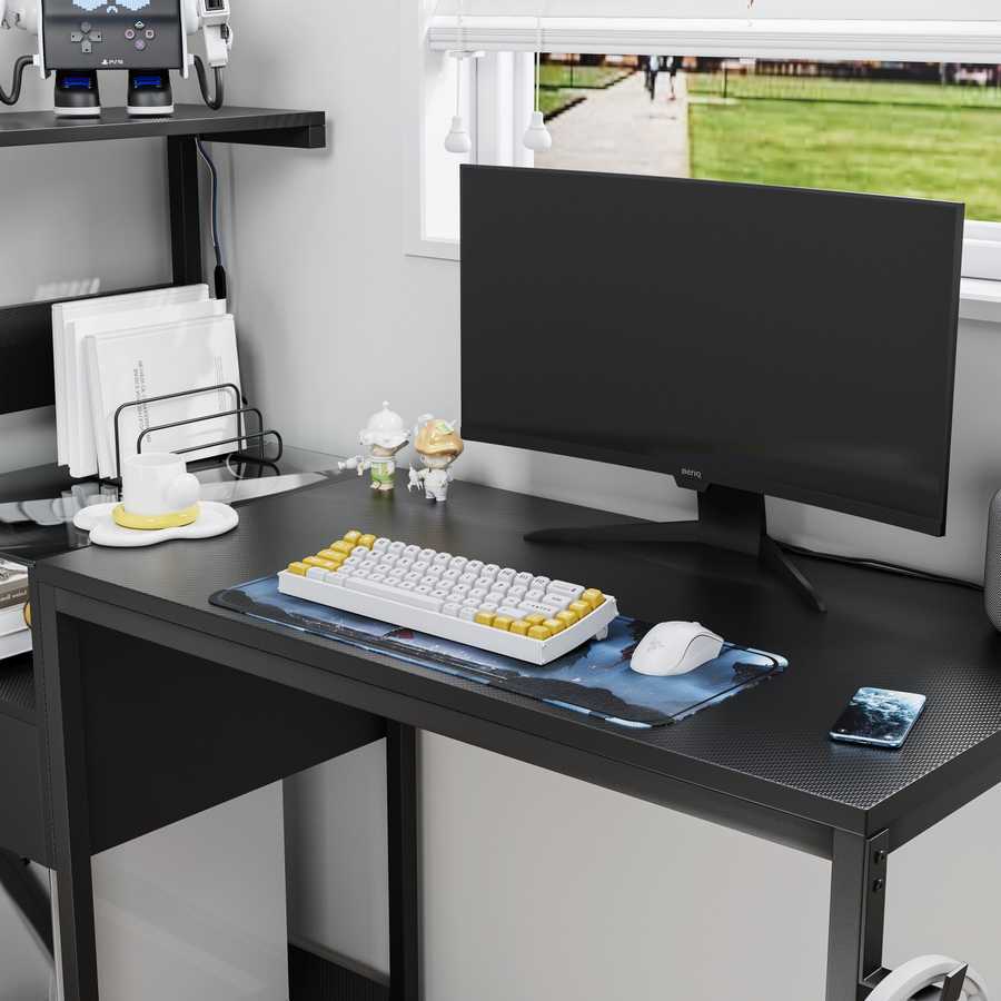 Detail of black computer desk with USB charging station, power outlet, and spacious desktop for monitor and accessories.