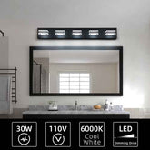 A modern rectangular bathroom vanity light with four illuminated LED bulbs mounted above a large black-framed mirror. The bathroom has a white wall, a gray marble countertop, and a sink.