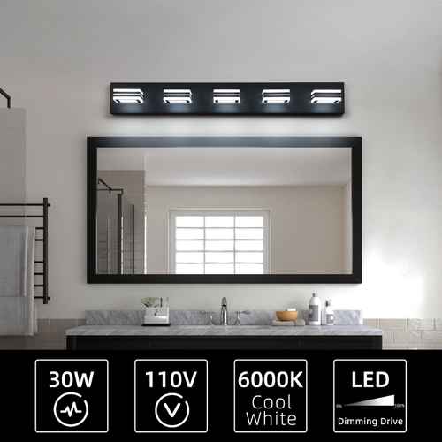 A modern rectangular bathroom vanity light with four illuminated LED bulbs mounted above a large black-framed mirror. The bathroom has a white wall, a gray marble countertop, and a sink.