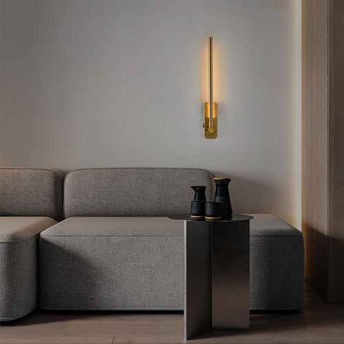 Modern living room with a gray sofa, side table, and wall-mounted gold light fixture.