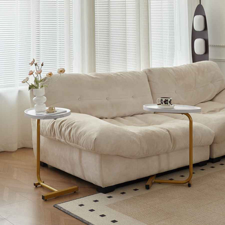 Beige sectional sofa with two small side tables in a living room setting.