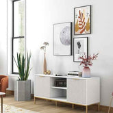 Close-up of a black flat-screen TV mounted on a white brick wall, with a white TV stand below and a wooden side table to the right