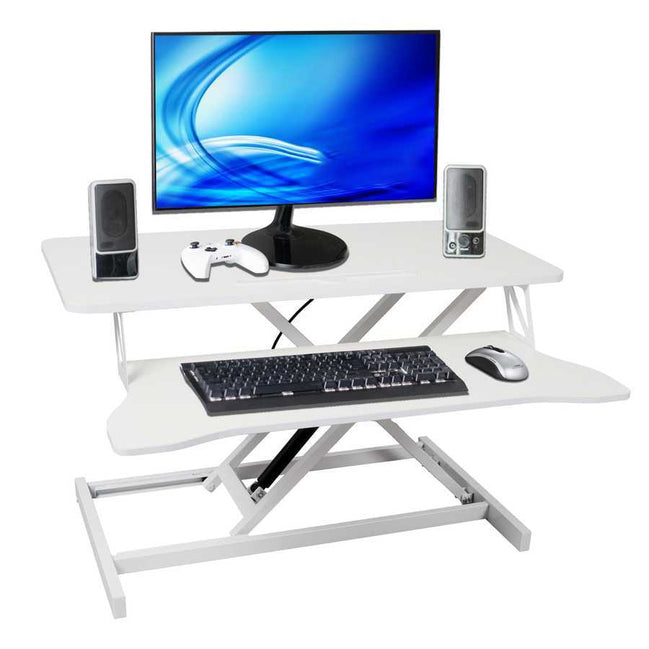 Adjustable standing laptop desk with keyboard tray, shown with monitor, speakers, and accessories. Ergonomic height-adjustable design for workspace comfort.