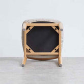 Modern wooden stool with a black seat on a light gray floor.