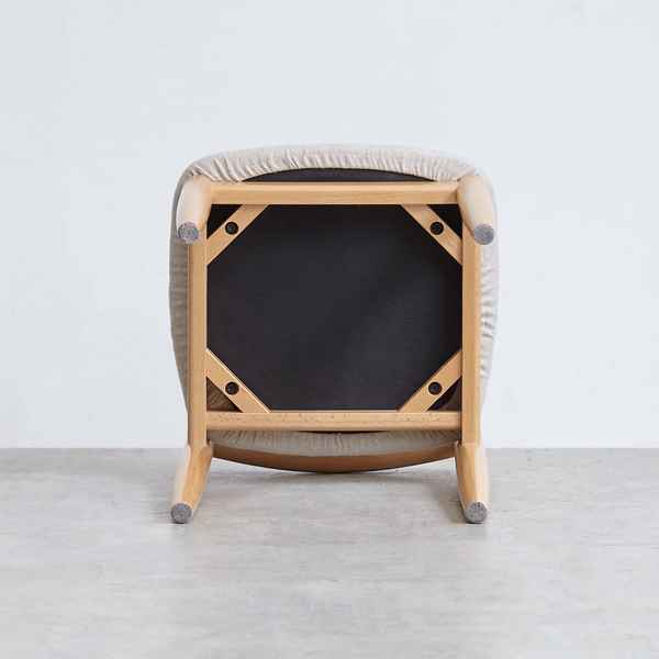 Modern wooden stool with a black seat on a light gray floor.