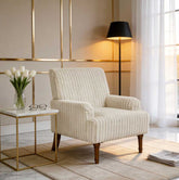 Beige armchair in a stylish living room with a side table and lamp.