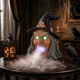 Witch Halloween decor with glowing green eyes, wide open mouth emitting fog, black pointed hat with skull detail, spooky indoor setting