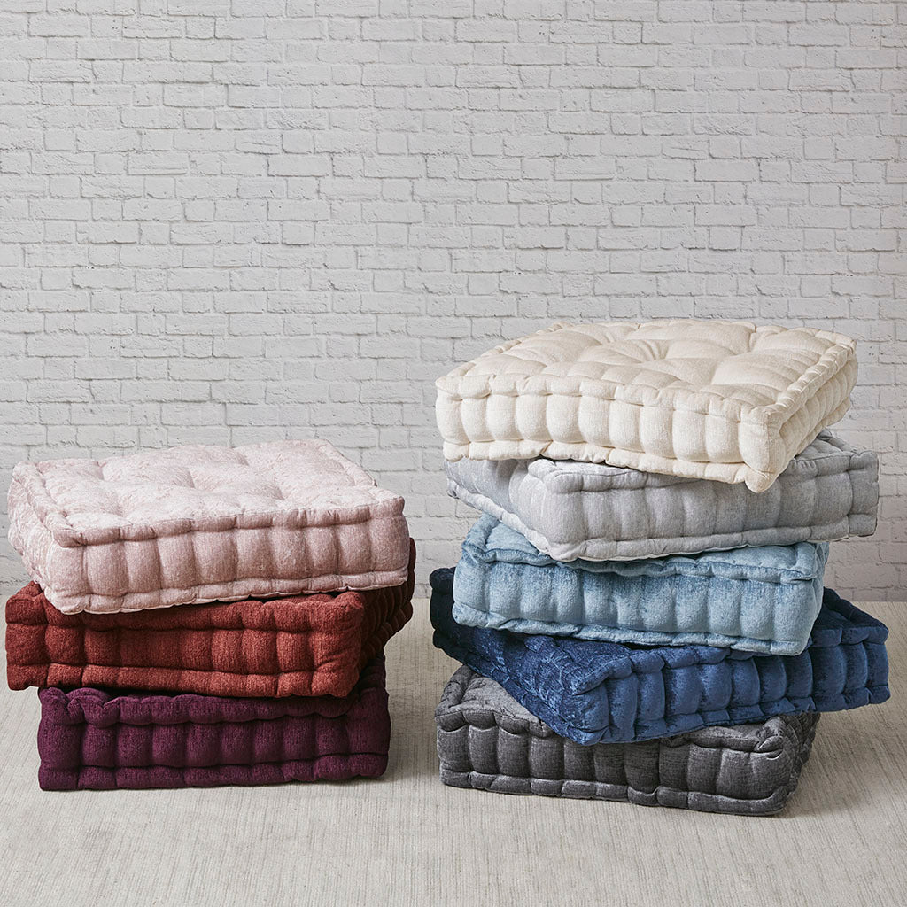 Stacks of quilted seat cushions in various colors against a white brick wall.