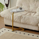 Side table with a cup and book next to a beige sofa on a patterned rug.