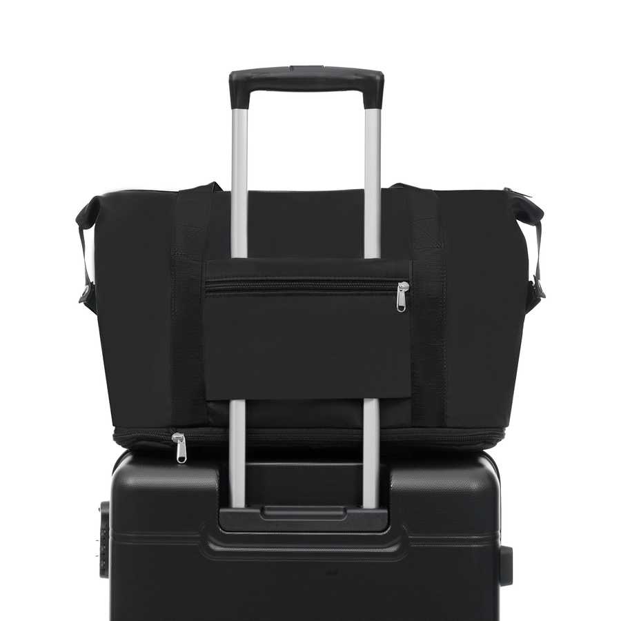 Black duffel bag with a pocket on top of a black suitcase on a white background