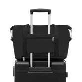 Black duffel bag with a pocket on top of a black suitcase on a white background
