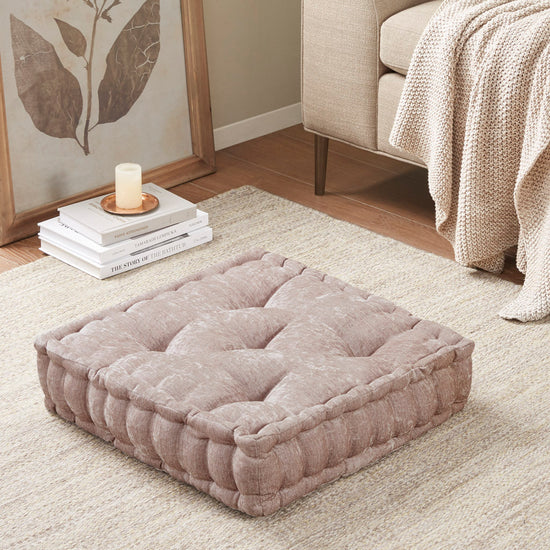 Gray pet bed on a carpeted floor with books and a candle in the background