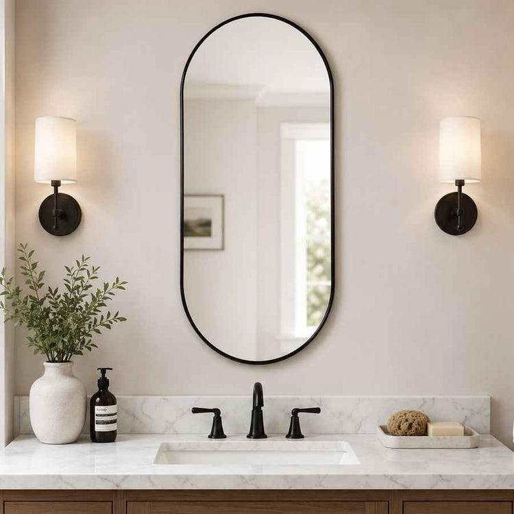 Bathroom vanity with oval mirror, lights, and decorative items.